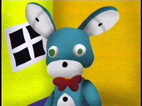 A screenshot of Bon, a blue animatronic rabbit, stnading in a yellow room with a white window.